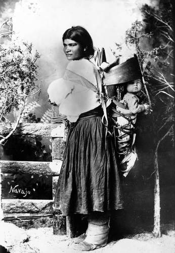 Navajo woman carrying child in a cradleboard. Cradleboards may be carried on the mother’s body as shown in this photo, but they may also be hung up in a tree or in the wall of a house. Navajo woman carrying child in a cradleboard. Cradleboards may be carried on the mother’s body as shown in this photo, but they may also be hung up in a tree or in the wall of a house.