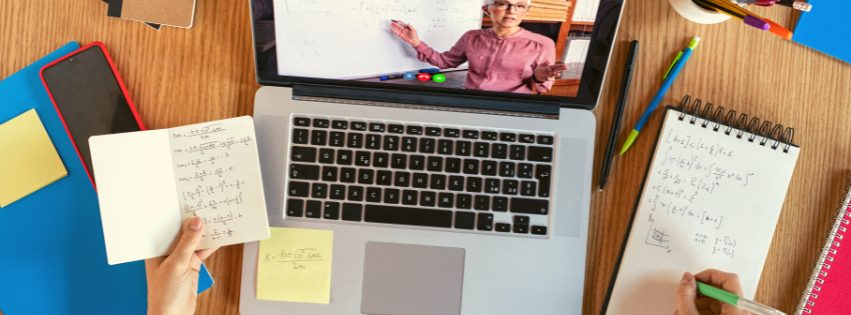 Student online learning at desk with laptop and books